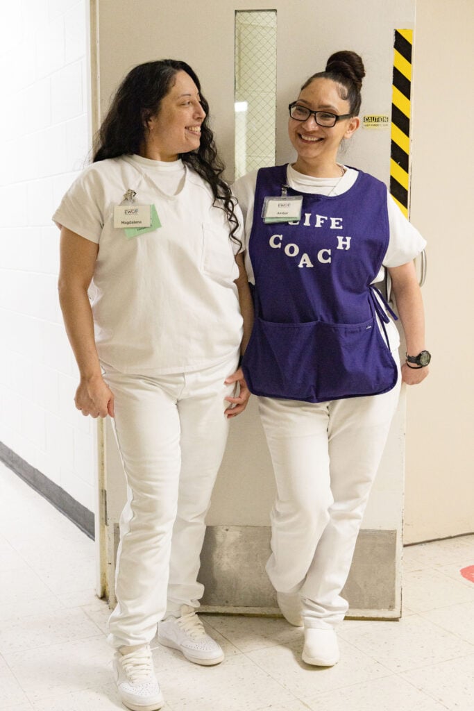Two EWOP participants standing together, one wearing a peer life coach vest