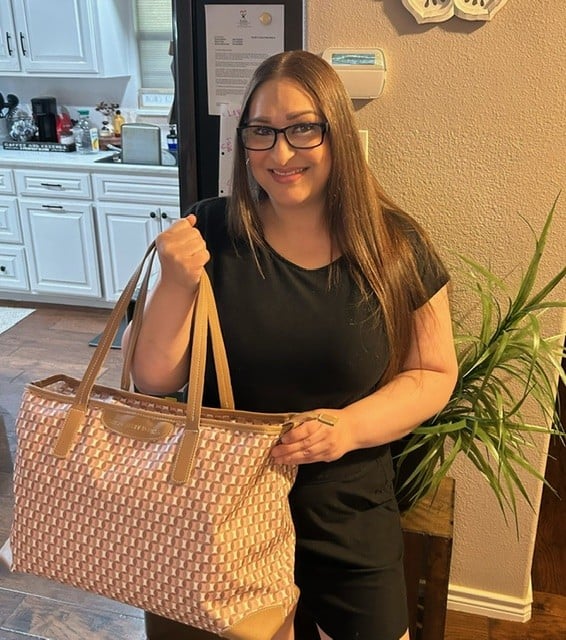 An EWOP graduate at home holding a bag of everyday essentials
